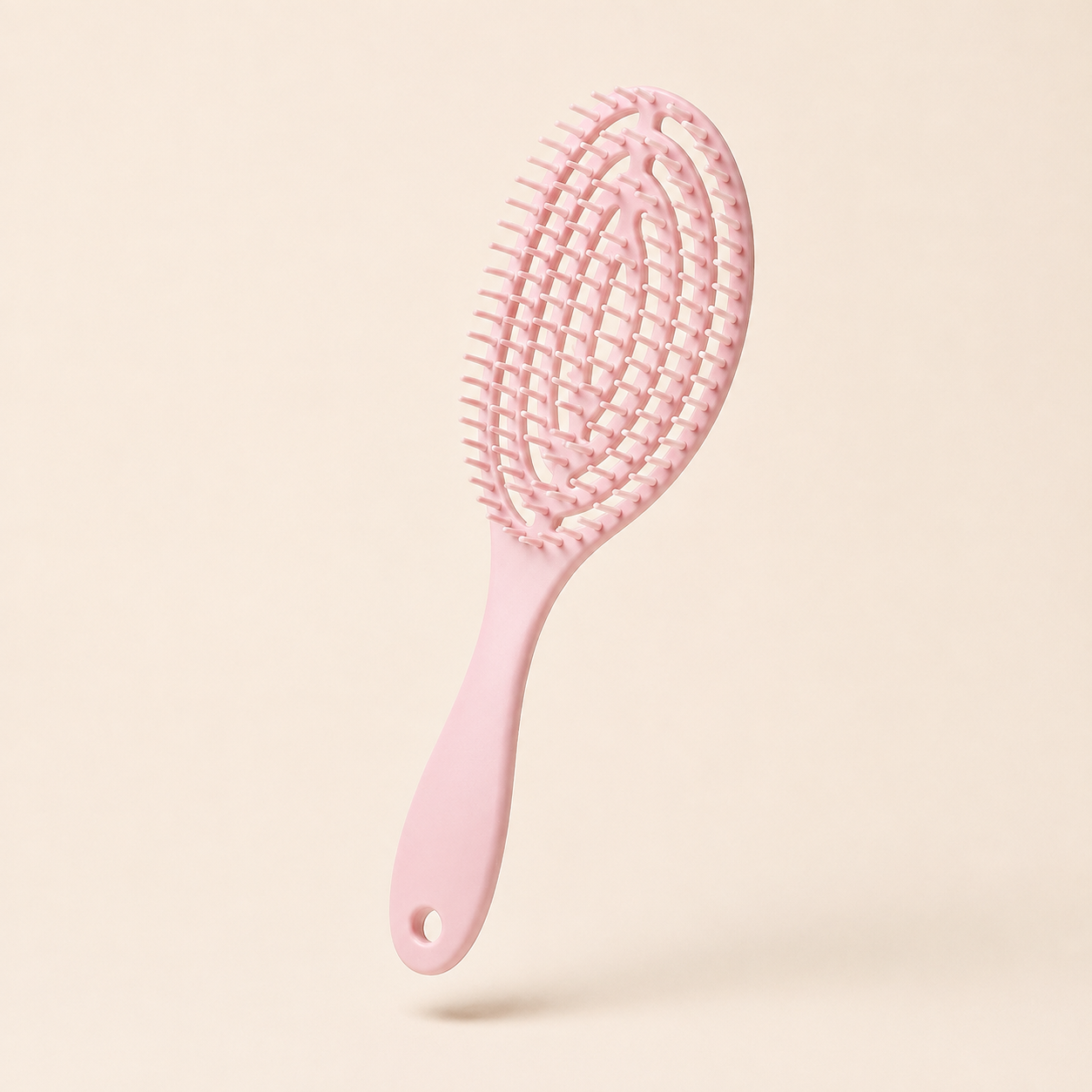 Glidura scalp massage brush in pink, angled view on an ivory background